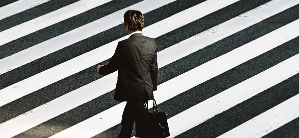 Photo d'un homme en costume, traversant une rue, sur un passage piéton